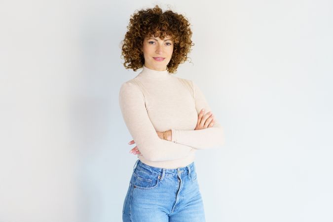 Confident woman with crossed arms against plain studio background