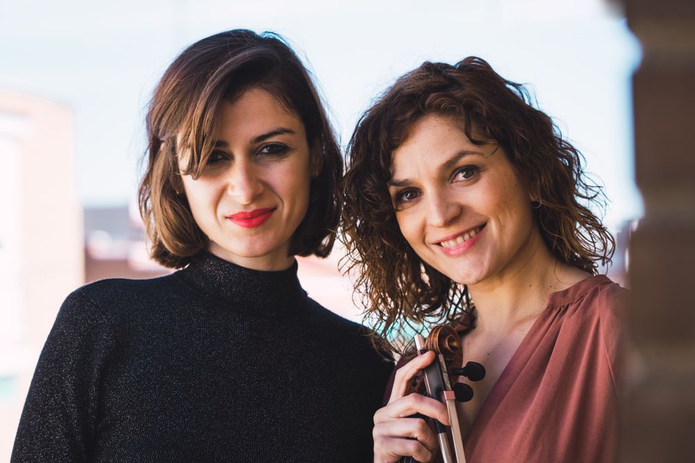 Young smiling women with violin on balcony