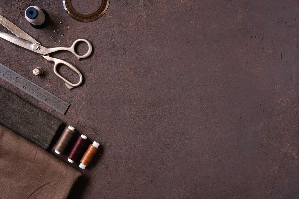 Sewing kit with thread, scissors, ruler on brown background