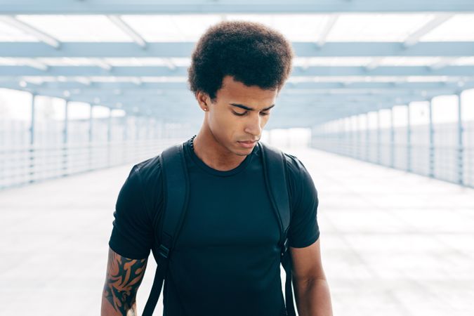 Young Black man on bridge with backpack