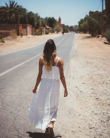 Woman in white dress walking in desert city