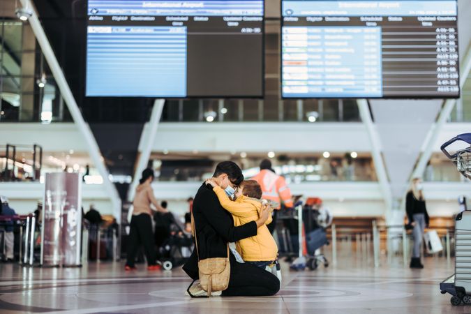 Woman and kid meeting at airport arrival after pandemic