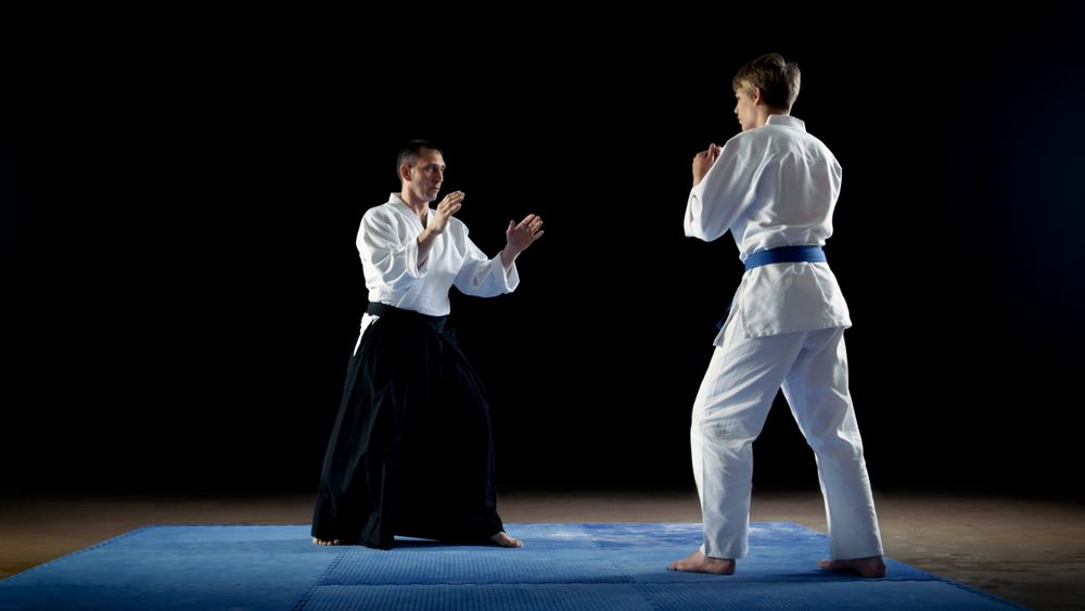 Martial Arts Master Wearing Traditional Samurai Hakamas Teaches Young Student Aikido Technique How To Reflect Fist Blows and Overpower Your Enemy.