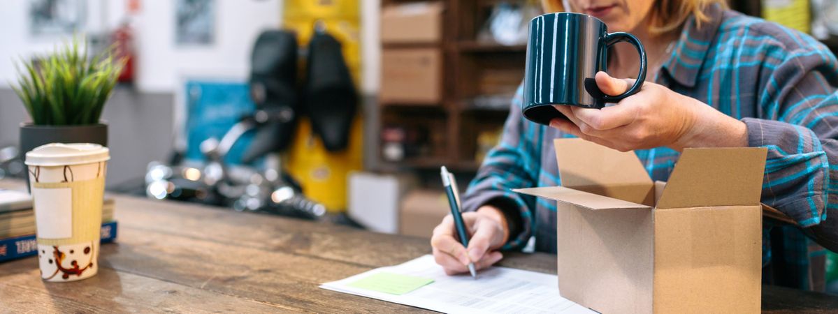 Banner of unrecognizable woman checking merchandise received by courier to sell in local store