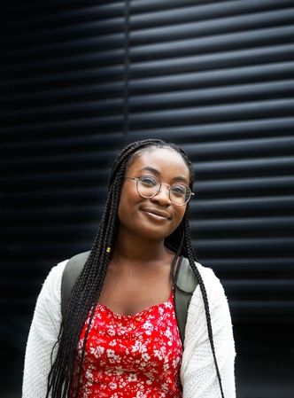 Smiling young Black woman in glasses against dark background