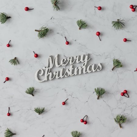 Holly and pine pattern on marble background with the words “Merry Christmas”