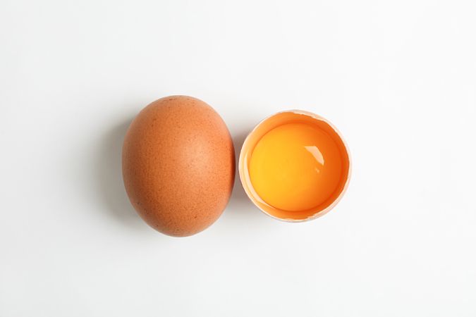 Whole egg and half egg with yolk on blank background, space for text and top view