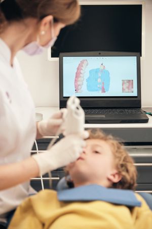 Unrecognizable dentist making 3D teeth scanning of boy