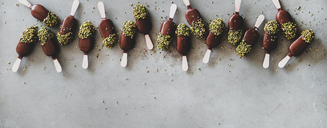 Ice cream chocolate pistachio popsicles, grey background, copy space