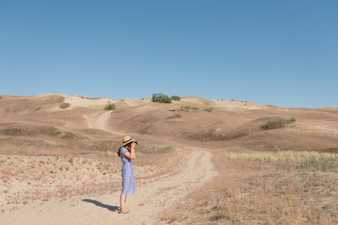 Young female photographer on dry field