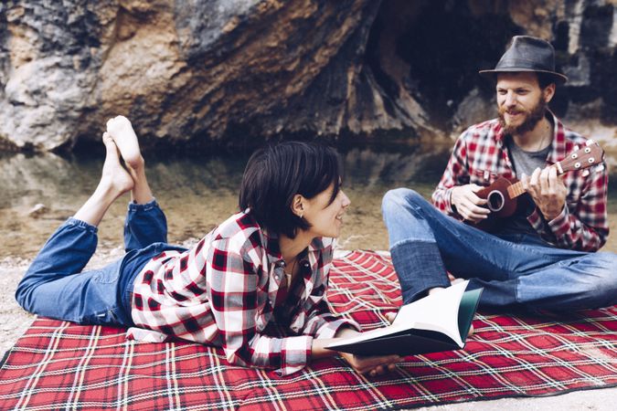 Chilling couple with book and guitar on shore