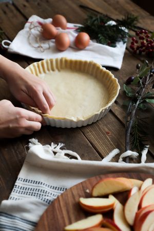 unrecognizable woman making a apple pie on a wooden table