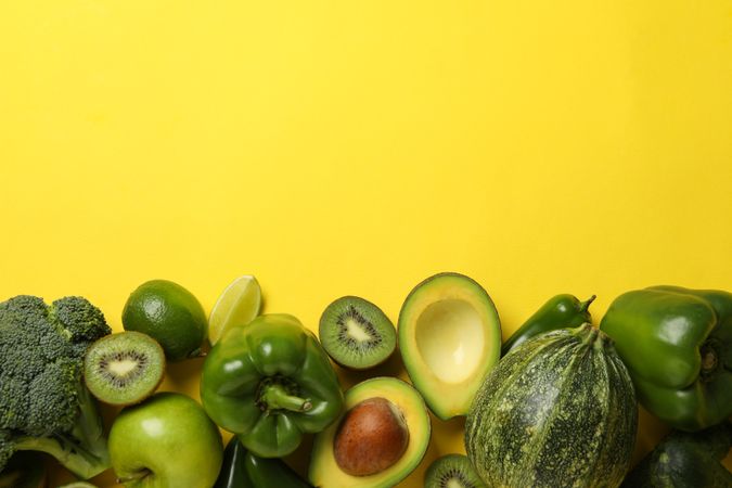 Green vegetables and fruits on yellow background