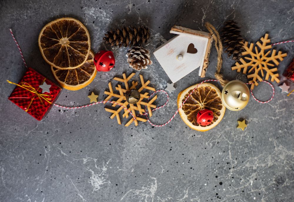 Top view of wooden snowflakes, gift boxes, dried orange slices and pine cones on marble table