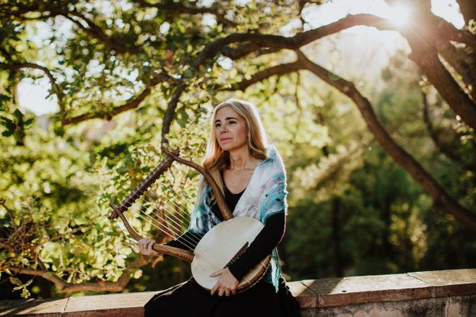 Cheerful charming woman with lyre in garden