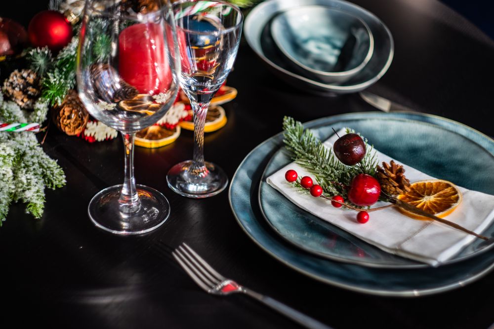 Blue holiday table setting with decorative berries and dried orange slice