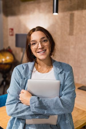 Happy female manager with laptop in workplace