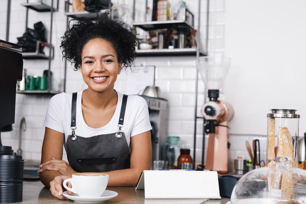 Smiling barista  with cappuccino at bar