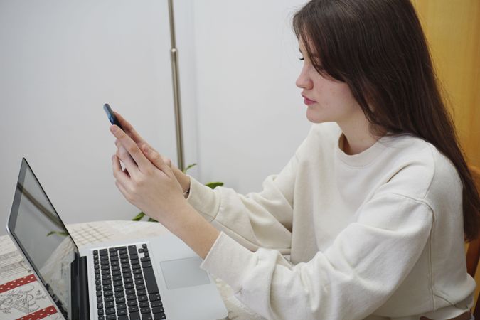 Teenage girl using smartphone and computer