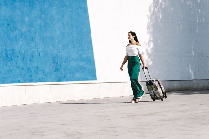 Side view of young female tourist carrying a baggage while walking in street