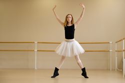 Ballerina in shoes and tutu, arms raised, performing modern dance