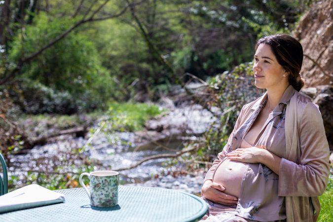 Relaxed pregnant young woman reading newspaper outside