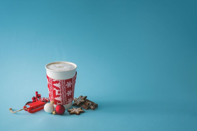 To-go cup of coffee with Christmas sleeve, decorations and cookies
