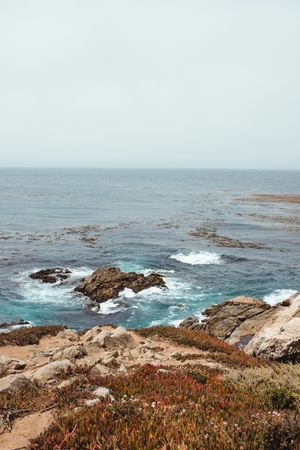 Blue waves washing rocky seashore in bright day