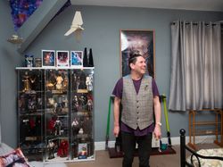 Man smiling at home in front of figuring collection bDeGp0