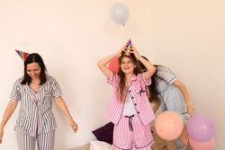 Mother and daughters celebrating with party hats and balloons.