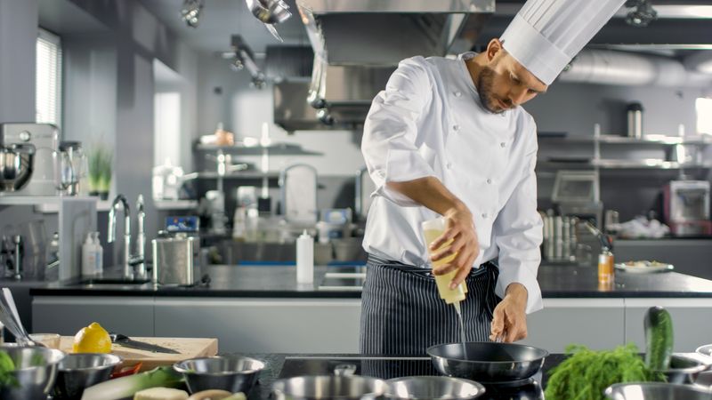 Professional Chef Working in a Famous Restaurant Kitchen. Starts Preparing His Specialized Dish, Turns on Stove and Puts Pan with Oil on it.