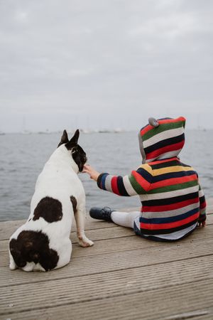 Anonymous kid petting dog on pier