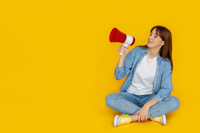 Concept of people, woman with megaphone on yellow background