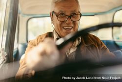 Happy mature man wearing eyeglasses driving a car, shot from inside the car 4Opjab