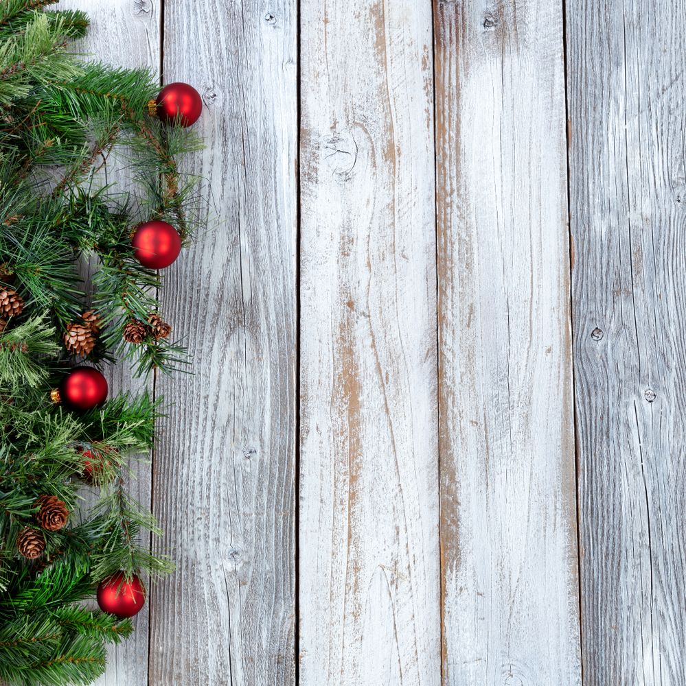 Christmas background with evergreen branches and red ornaments on aged wood