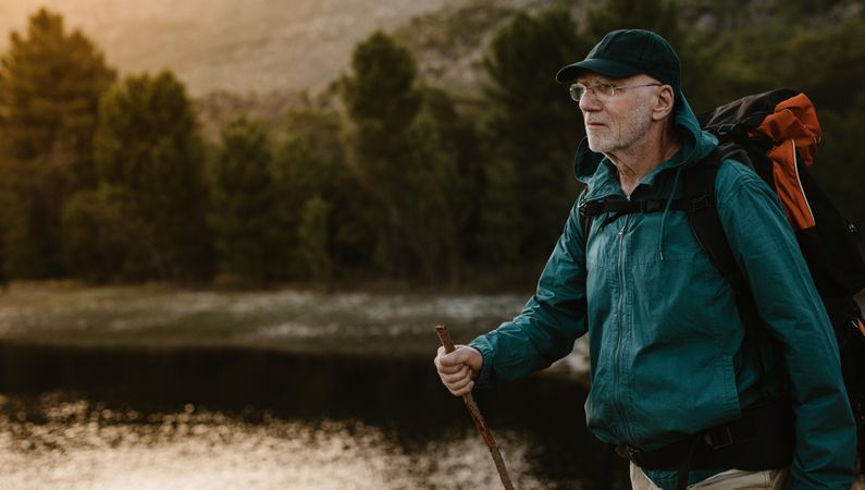 Mature man walking by a river on mountain trail