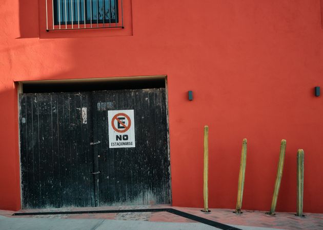 Red building and garage with no parking sign in Spanish