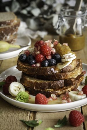Honey pouring over fried toasts with fruit