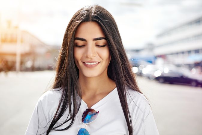 Woman  with long hair looking down with smile on sunny day