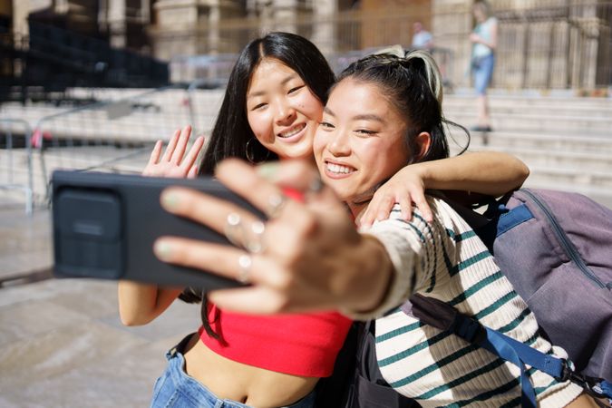 Two smiling women taking selfie in front of Church in Spain