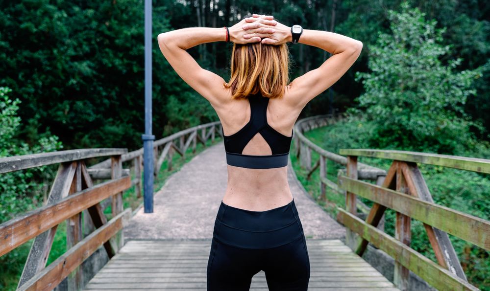 Unrecognizable sportswoman doing stretching arms outdoors
