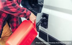 Male in red checkered shirt filling up van with gas can, closeup bY9J1b