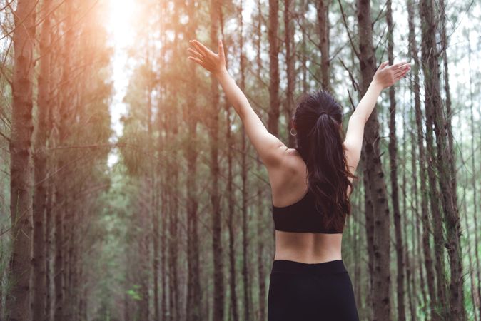 Woman stretching arms out in forest