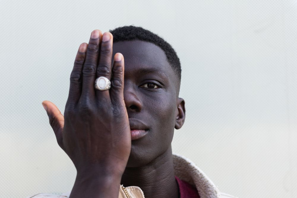 Stylish Black man covering face and looking at camera