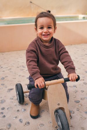 Content girl on wooden bicycle in daytime