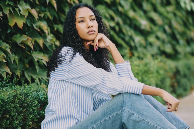A Contemporary Fashion Portrait of a Thoughtful Woman Surrounded by Lush Nature Elements