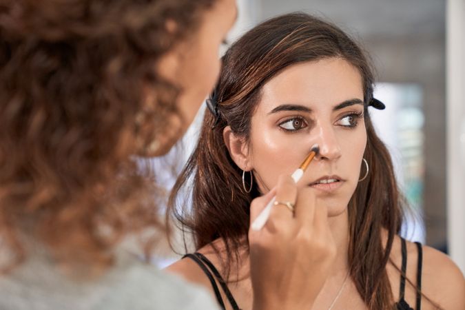 Faceless woman applying makeup on model