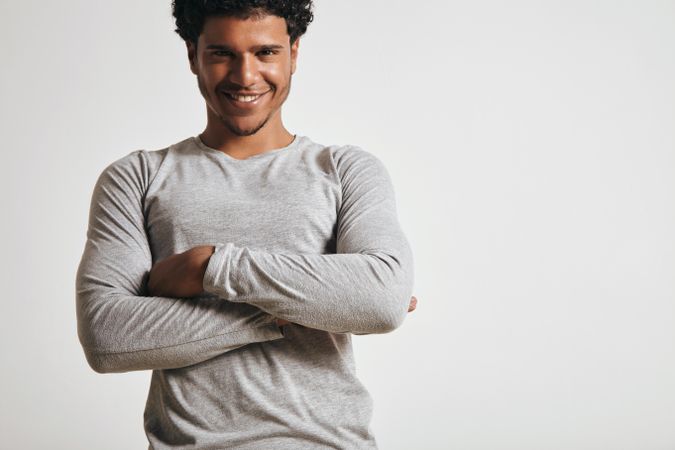 Smiling man in grey with arms crossed in studio shoot