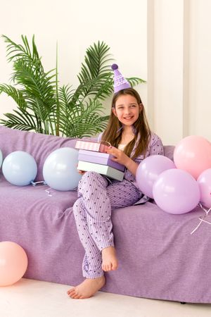 Smiling girl celebrating her birthday with balloons and gifts.