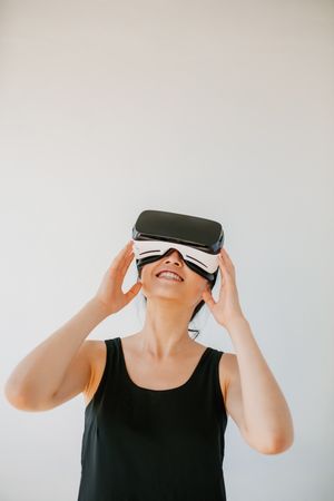 Young woman using the virtual reality headset against grey background